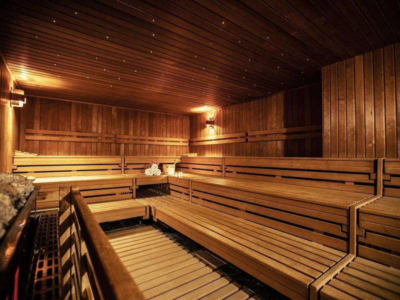 Innenraum einer Sauna mit Holzverkleidung, mehrstufigen Sitzbänken und warmem Licht.