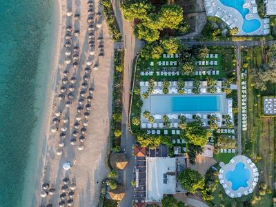 Luftaufnahme eines Resorts mit Pool, Liegestühlen und Strand am Meer
