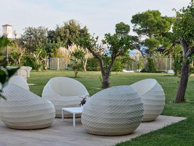 Moderner weißer Sitzbereich mit runden Stühlen und einem kleinen Tisch im Garten
