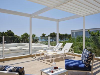 Dachterrasse mit weißen Liegestühlen und blau gemusterten Sitzkissen unter einem Sonnenschutz