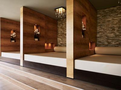 Modernes Spa-Bereich mit Liegen, Holztrennwänden und stimmungsvoller Beleuchtung.