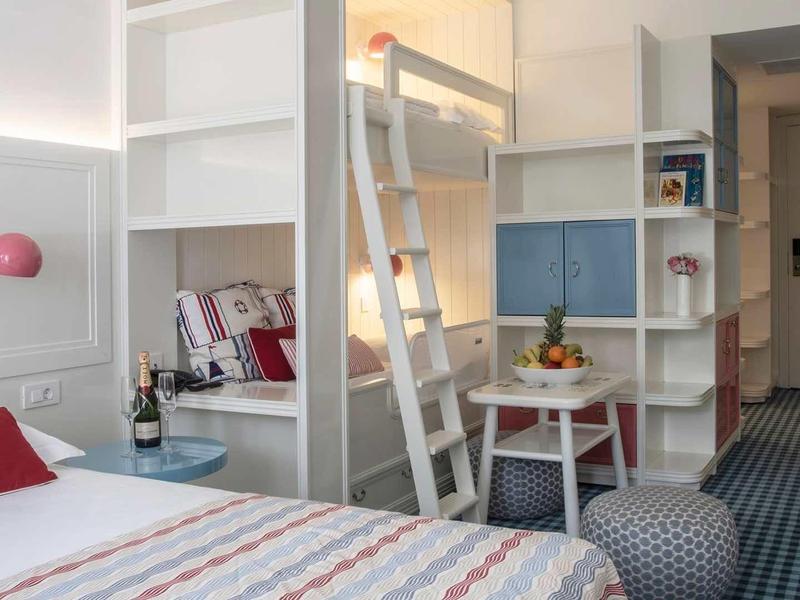 Modern hotelkamer met stapelbed, bureau en gezellige sfeer.