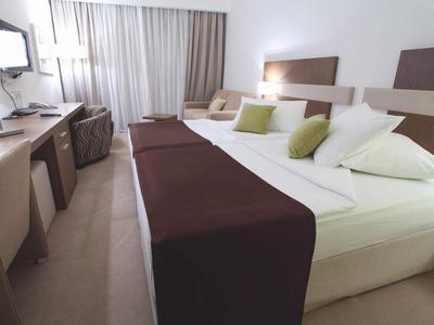 Modernes Hotelzimmer mit Doppelbett, Schreibtisch, Stühlen und einem Fernseher.