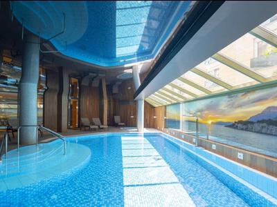 Moderner Innenpool mit großer Glasfront und Blick auf Berge bei Sonnenuntergang