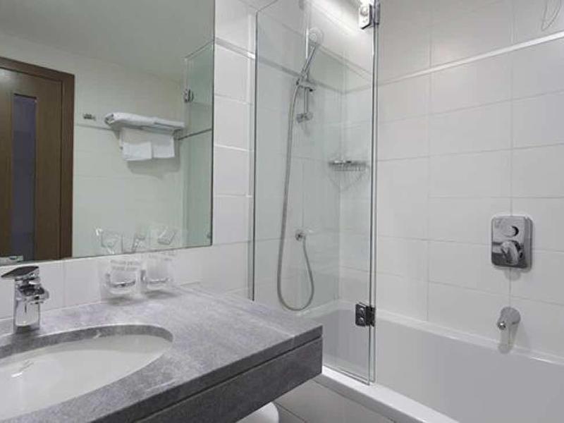 Moderne, helle Badezimmer mit großer Spiegelwand, sanitärer Ausstattung und Dusche mit Glaswand.