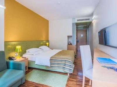 Nowoczesny pokój hotelowy z wygodnym łóżkiem podwójnym, biurkiem i przytulnym fotelem.