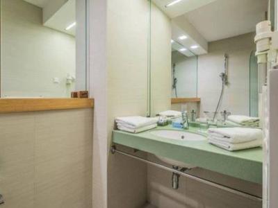 Kompaktowa łazienka z dużym lustrem, umywalką, ręcznikami i suszarką do włosów.