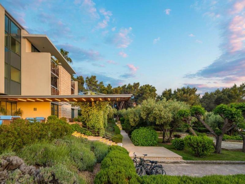 Budynek hotelu otoczony zielonymi drzewami i krzewami pod niebieskim niebem o zachodzie słońca