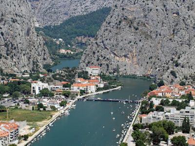 Vista di una città sul fiume, circondata da scogliere rocciose con un ponte sull'acqua.