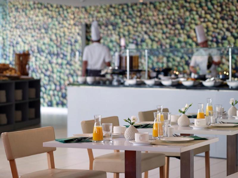 Ristorante moderno con tavoli apparecchiati e chef sullo sfondo.