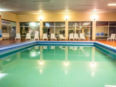 Piscina interna con lettini e grandi finestre in un hotel.