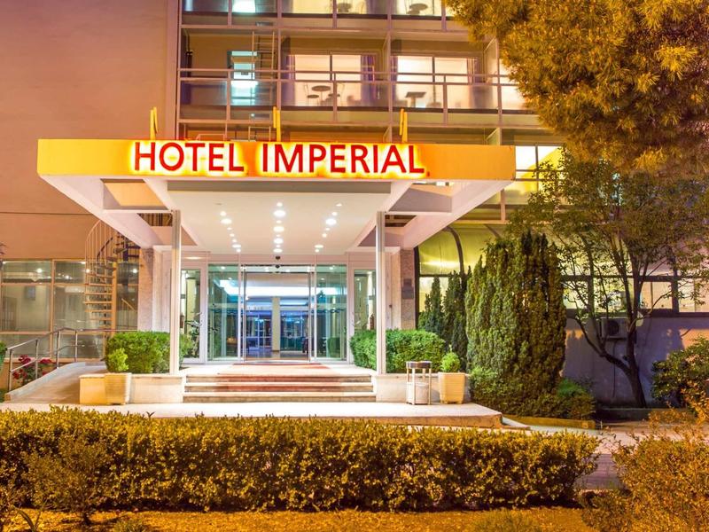 Ingresso dell'hotel illuminato con insegna 'Hotel Imperial' e piante di notte.