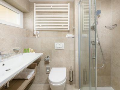 Komfortables Badezimmer mit Waschbecken, Toilette und Glaskabinen-Dusche in hellen Tönen.