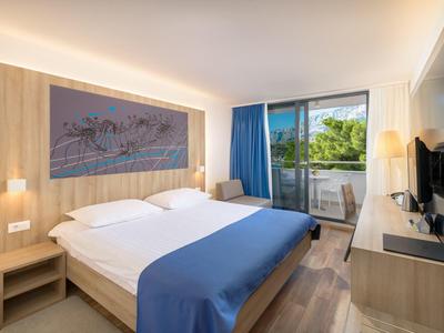 Modernes Hotelzimmer mit Doppelbett, Holzvertäfelung, Balkon und Flachbildfernseher.