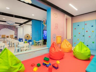 Buntes Kinderspielzimmer mit Sitzsäcken, Spielzeug und Kletterwand in hellem Raum.