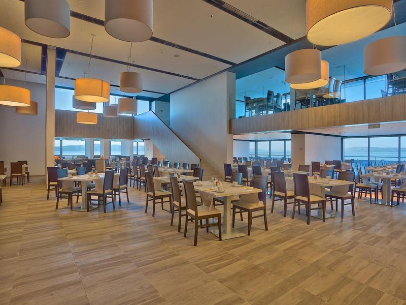 Großer, moderner Speisesaal mit Holzboden und zahlreichen Tischen und Stühlen.