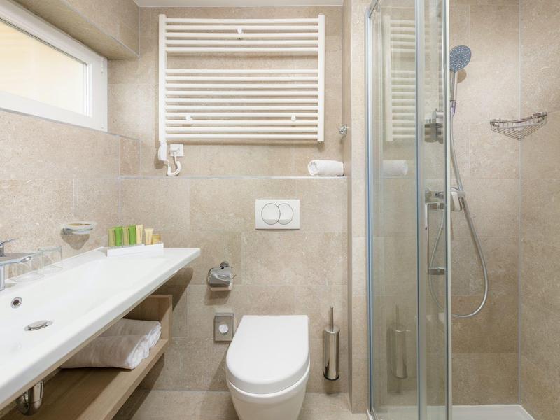 Komfortables Badezimmer mit Waschbecken, Toilette und Glaskabinen-Dusche in hellen Tönen.