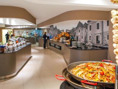 Espace buffet d'hôtel avec une variété de plats et une fresque murale décorative.