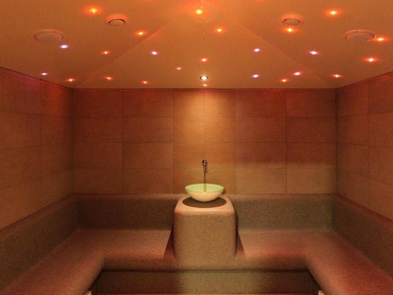 Salle de bien-être sombre avec bancs en pierre et fontaine d'eau centrale