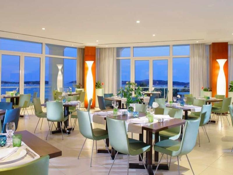 Restaurant d'hôtel élégant avec grandes fenêtres et vue sur mer dans un design lumineux et moderne.