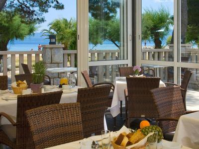 Terrasse eines Restaurants mit gedeckten Tischen und Blick auf das Meer und Bäume