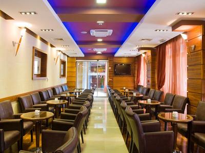 Modernes Hotelrestaurant mit langen Reihen von Tischen und Stühlen, warmes Licht und Holzverkleidung.