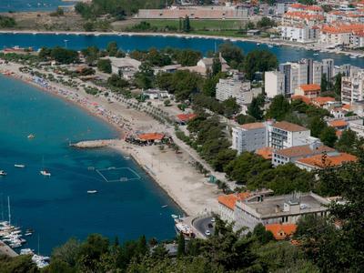 Vue aérienne d'une ville côtière avec plage, bateaux et immeubles modernes au bord de la mer.