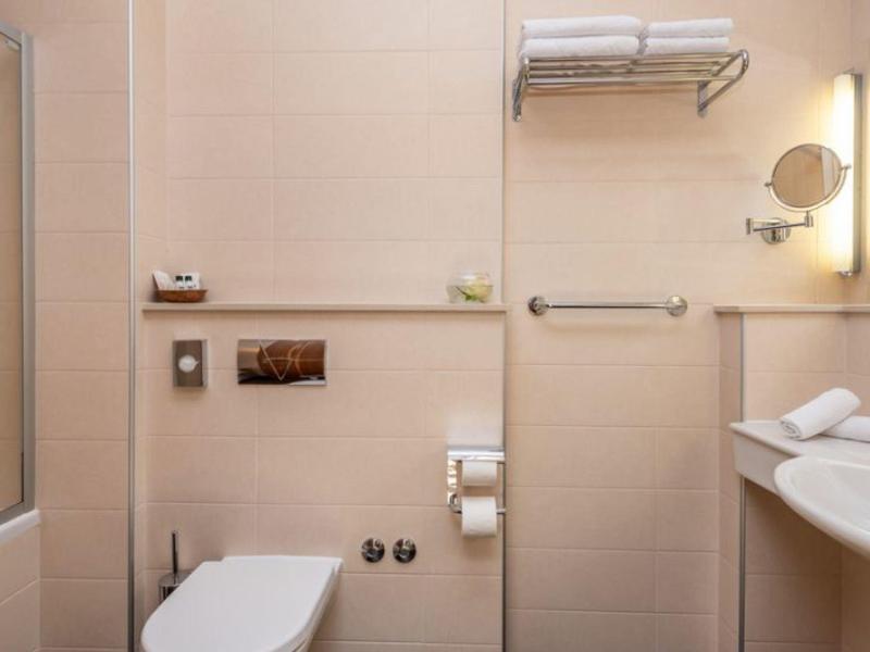 Salle de bain d'hôtel moderne beige avec toilettes, lavabo et serviettes.