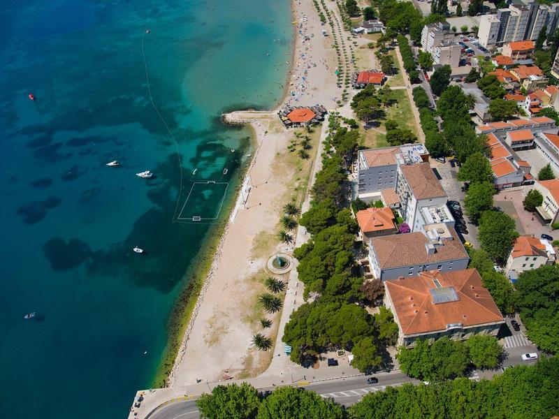 Vue aérienne d'une plage avec des bâtiments et une mer turquoise.