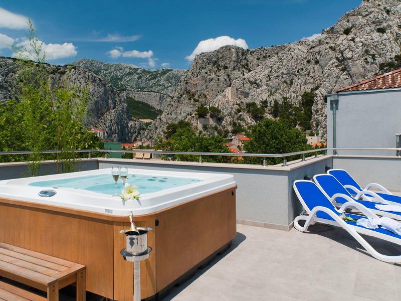 Bain à remous et chaises longues sur terrasse avec vue sur la montagne par ciel clair