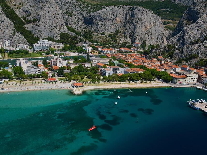 Plage et port dans une ville côtière avec montagnes en arrière-plan et eau claire.