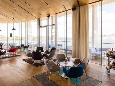 Modern hotel restaurant with floor-to-ceiling windows overlooking the water.