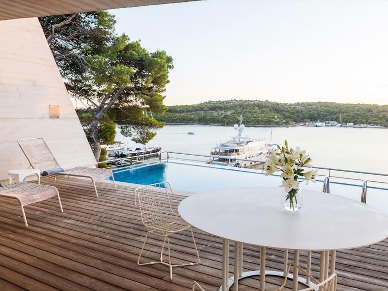 Terrasse avec piscine et chaises longues donnant sur la mer et les yachts.