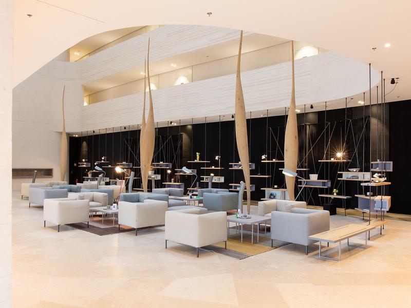 Design moderne du hall d'hôtel avec mobilier blanc et colonnes en bois sculptural.