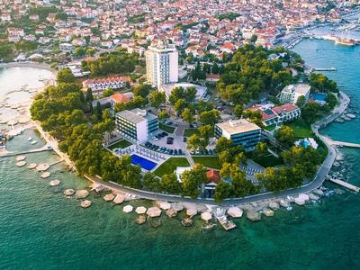 Luftaufnahme einer kleinen Halbinsel mit Hotels und Stränden in einer Küstenstadt.