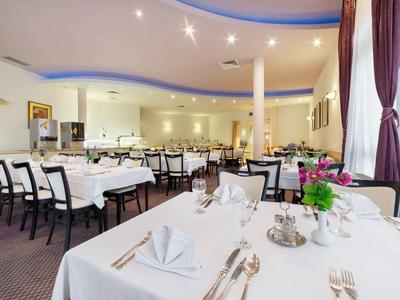 Eleganter Hotel-Speisesaal mit weiß gedeckten Tischen und violetten Vorhängen.