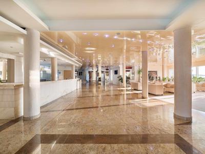 Große Hotellobby mit Säulen und Marmorboden in warmen Farben.