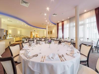 Elegancka sala jadalna z okrągłym stołem, białym obrusem i nakryciami przy naturalnym świetle.