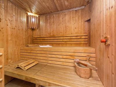 Sauna drewniana z wielopoziomowymi ławkami i wiadro z chochlą wewnątrz.
