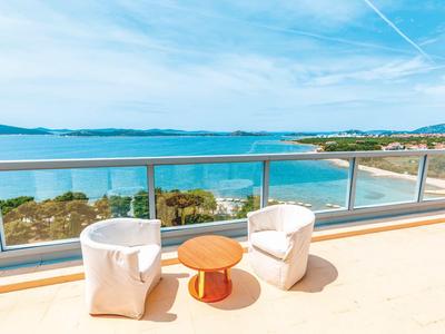 Balkon mit zwei weißen Sesseln und einem kleinen Holztisch mit Blick auf das Meer.