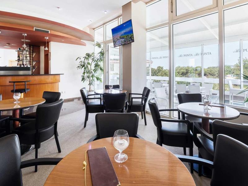 Nowoczesny bar hotelowy z czarnymi krzesłami, drewnianymi stołami i panoramicznymi oknami.