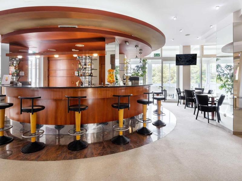 Nowoczesny bar hotelowy z okrągłym drewnianym barem, stołkami barowymi i miejscami do siedzenia.