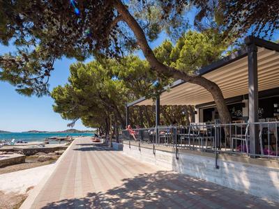 Sonnige Promenade am Strand mit Bäumen und Freiluftrestaurant mit Sitzbereich