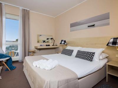 Modernes Schlafzimmer mit großem Bett, weißen Handtüchern, Schreibtisch und Balkon mit Blick.