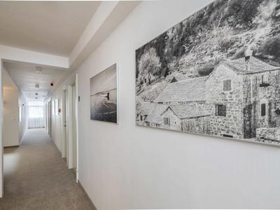 Heller Flur mit weißen Wänden, Teppichboden und zwei schwarz-weißen Landschaftsbildern an der Wand.