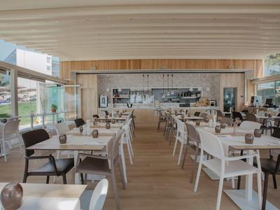 Moderner heller Essbereich mit weißen Stühlen, Holzboden und großer Fensterfront.