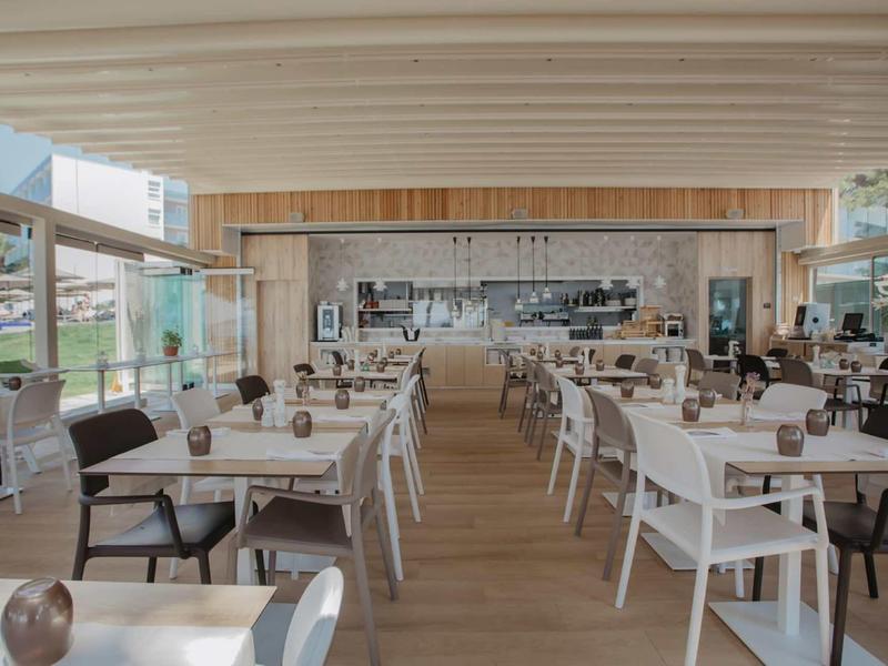 Moderner heller Essbereich mit weißen Stühlen, Holzboden und großer Fensterfront.