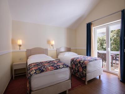 Kamer met twee eenpersoonsbedden, nachtkastje en terras met uitzicht op groen.