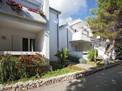 Biały budynek hotelu z kwietnikami i wybrukowaną ścieżką w słoneczną pogodę