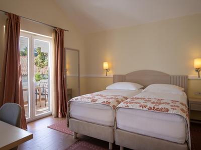 Helder ingerichte hotelkamer met twee eenpersoonsbedden en toegang tot een balkon.